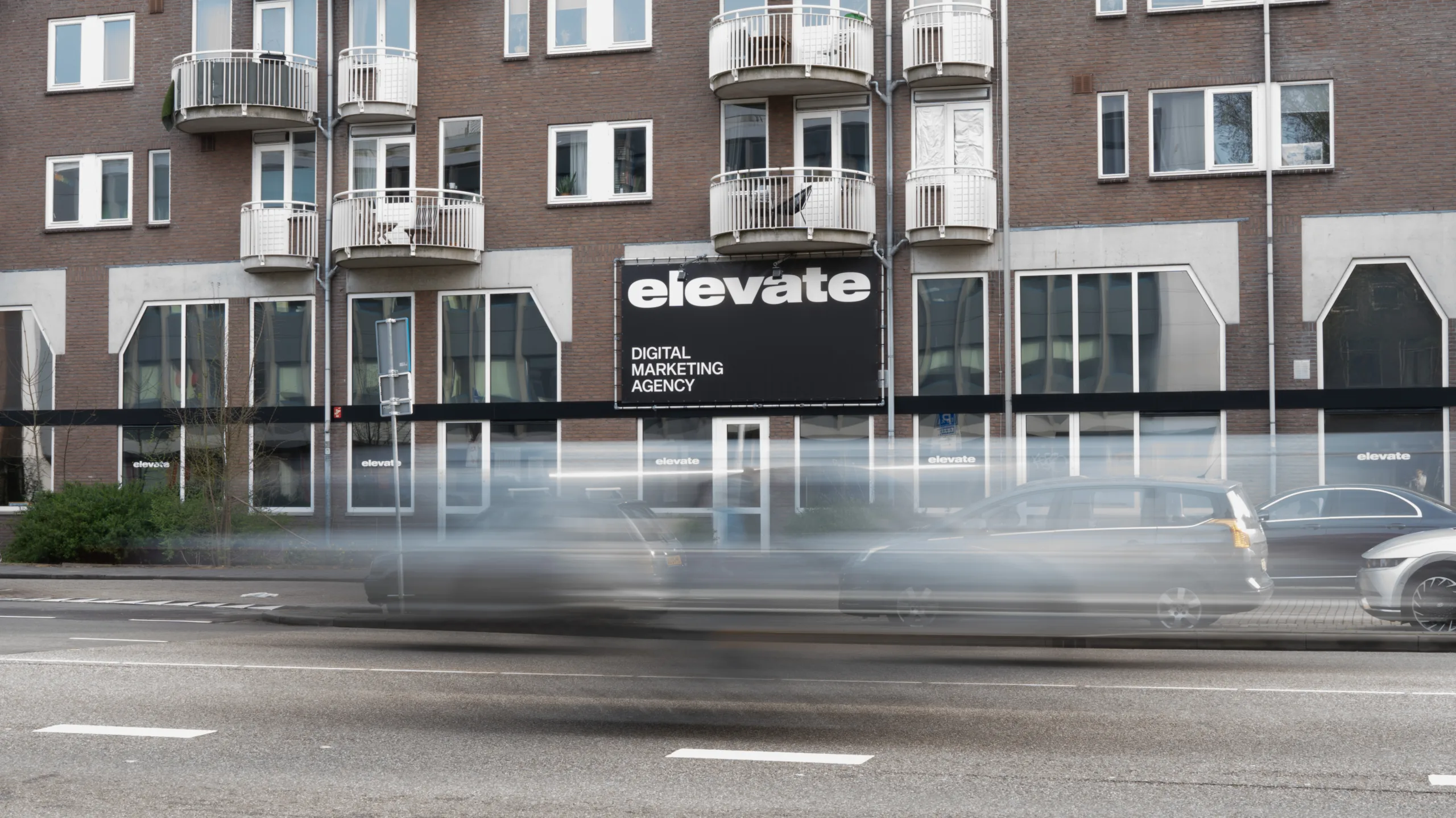 Het kantoorpand van Elevate Digital met auto's die langsrijden