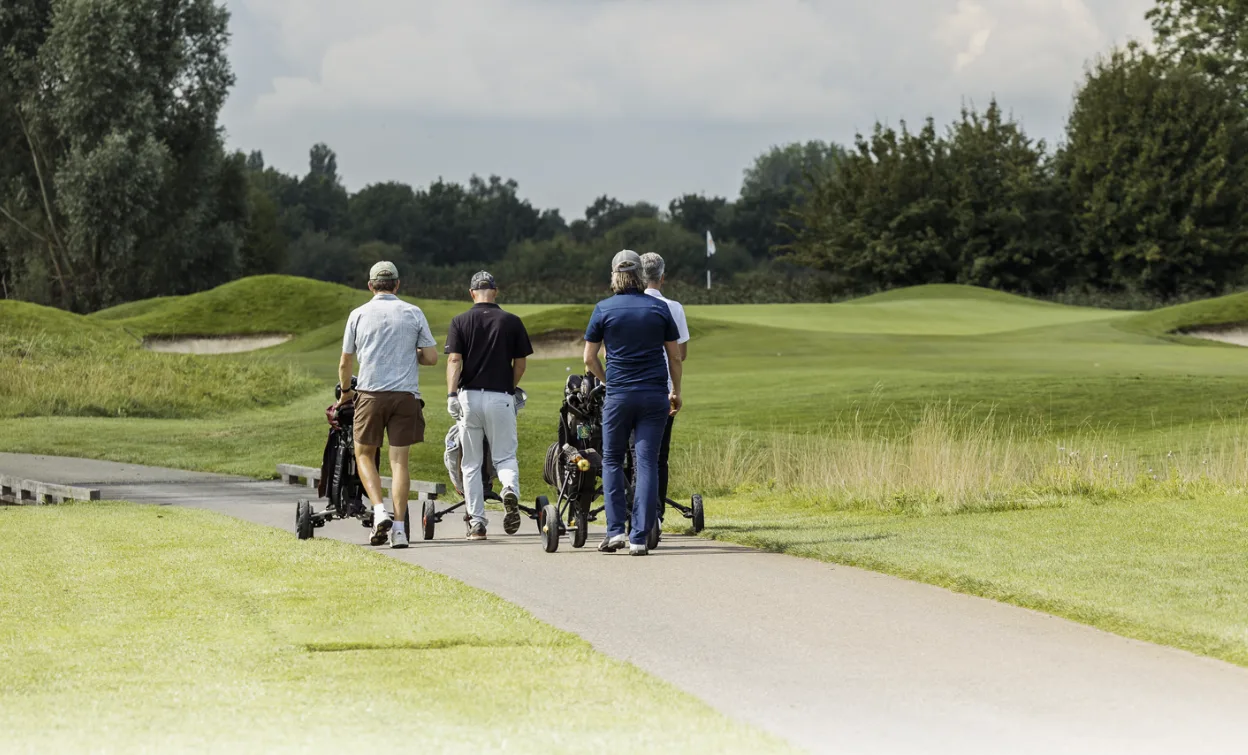 vier mannen op de golfbaan die onderweg zijn naar de volgende hole