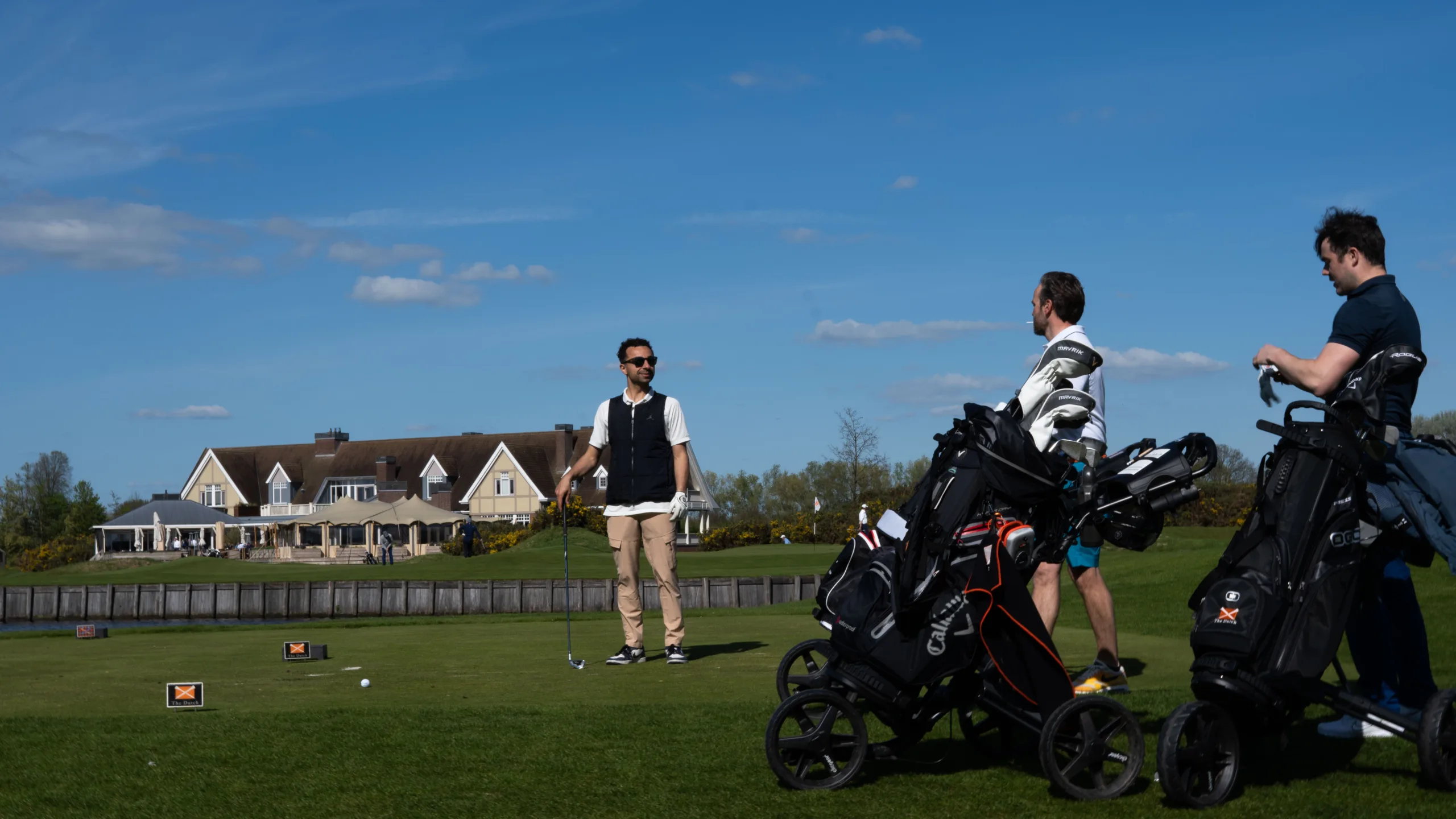 Drie mannen op een golfbaan klaar om af te slaan